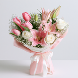 Pink lilies with tulips in a hand-tied bouquet