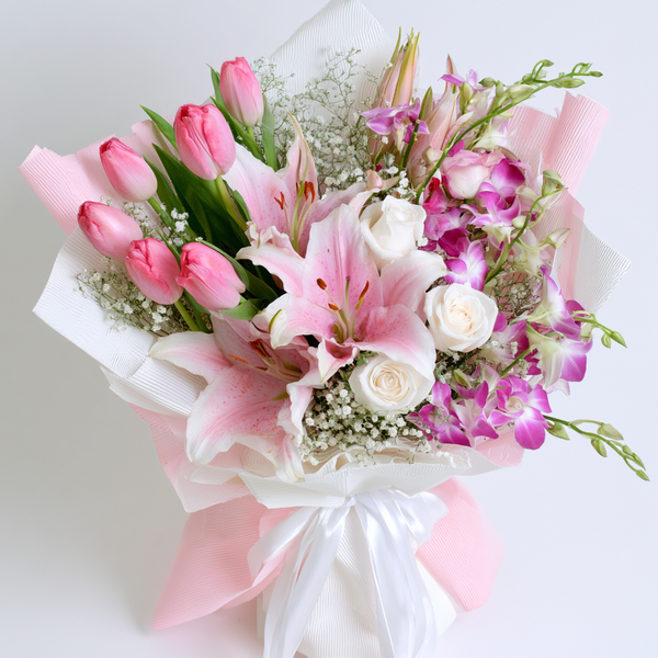 Pink tulips with pink lilies and white roses in a hand-tied bouquet